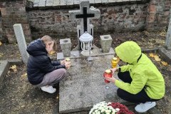 Uczniowie podczas  zapalania  zniczy na cmentarzu