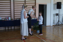 Uczeń klasy I odbierający nagrodę z rąk dyrektora i wychowawcy. 